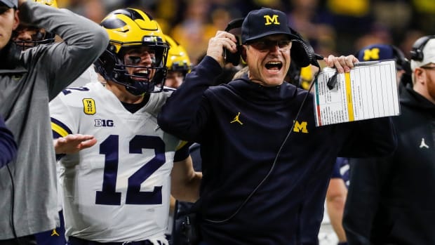 Michigan coach Jim Harbaugh and quarterback Cade McNamara celebrate a touchdown against Iowa during the first half of the Big Ten championship game.